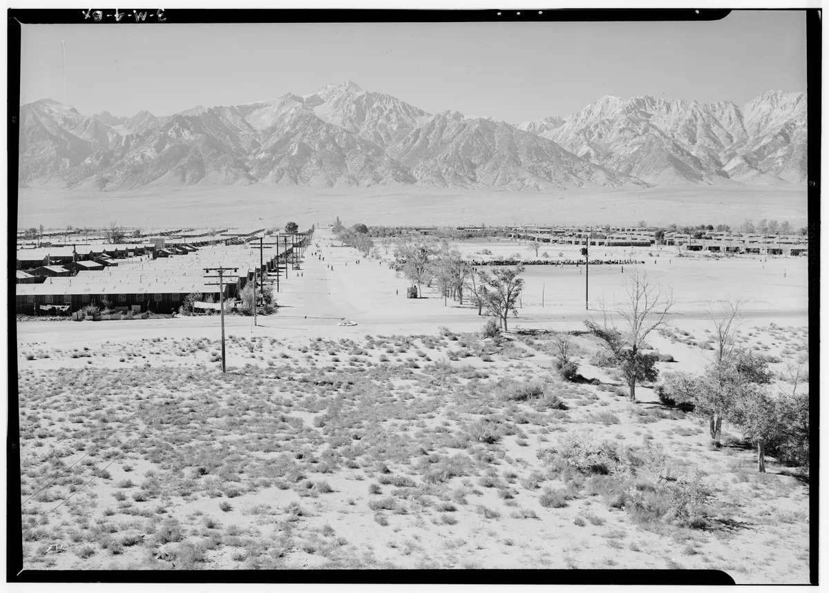 Ansel Adams’s elevated westward view of Manzanar, with roads and barracks beneath the Sierra Nevada and the negative border visible.