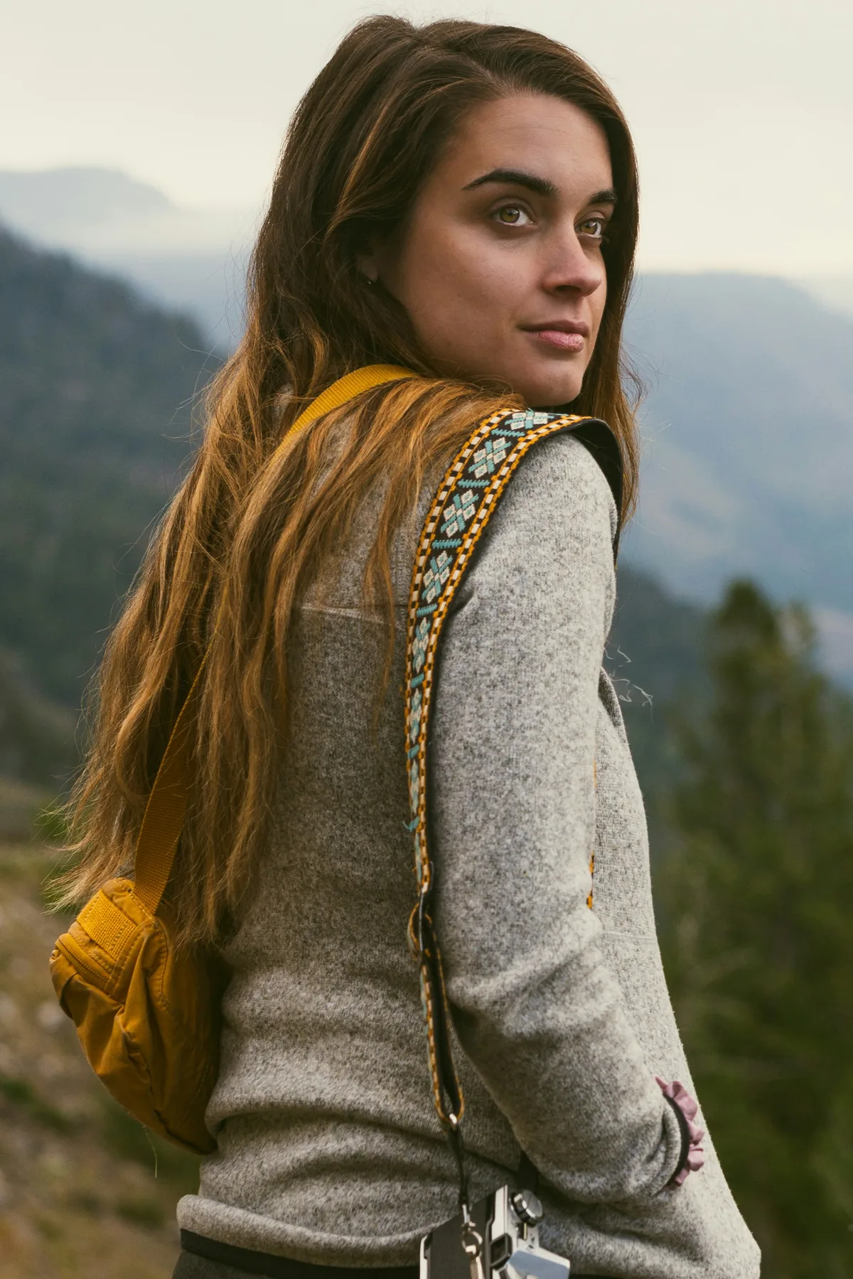 Woman looking over her shoulder in a mountainous landscape.