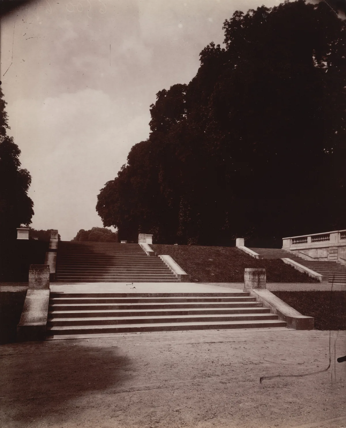 Atget’s vertical Saint-Cloud photograph of stone steps and balustrades beneath an opening framed by trees.