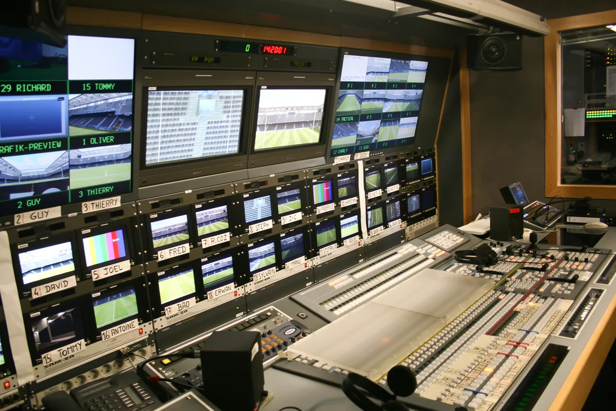 Labeled monitors and switching consoles inside a television broadcast truck.