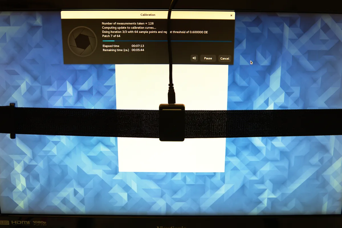 ColorHug2 colorimeter secured against a monitor while calibration software displays a measurement patch.