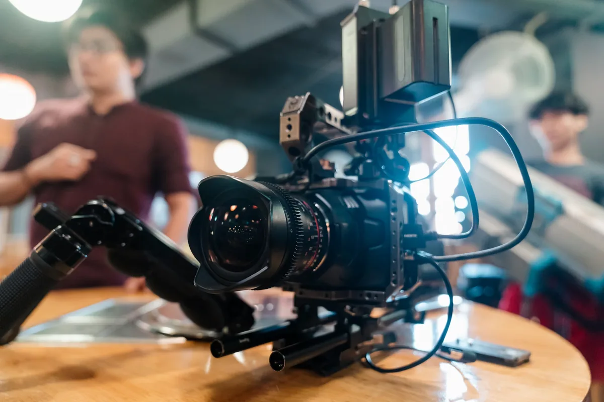 Cinema camera rig with a geared lens, external monitor and support rails on a table