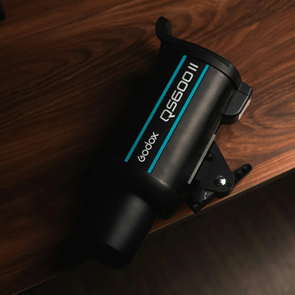 Godox QS600II studio flash lying diagonally on a wooden tabletop.