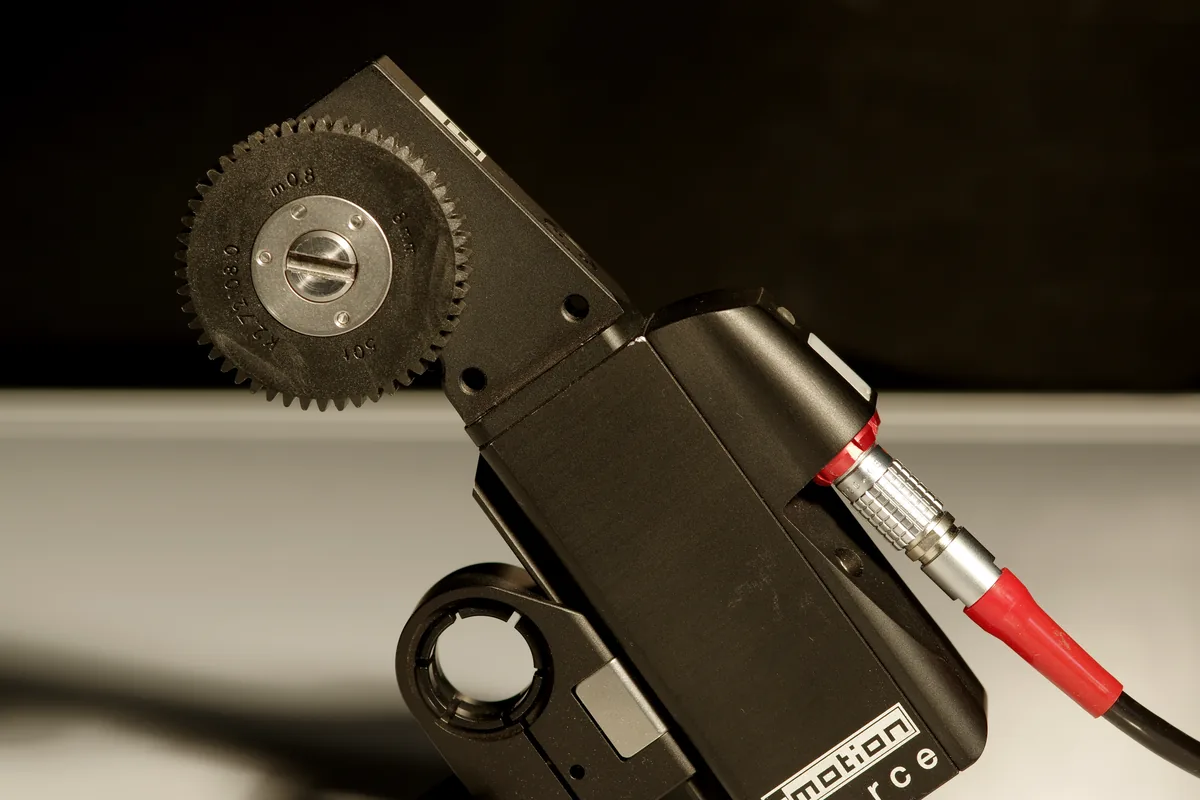 Close-up of a lens-control motor with a toothed gear and connected cable