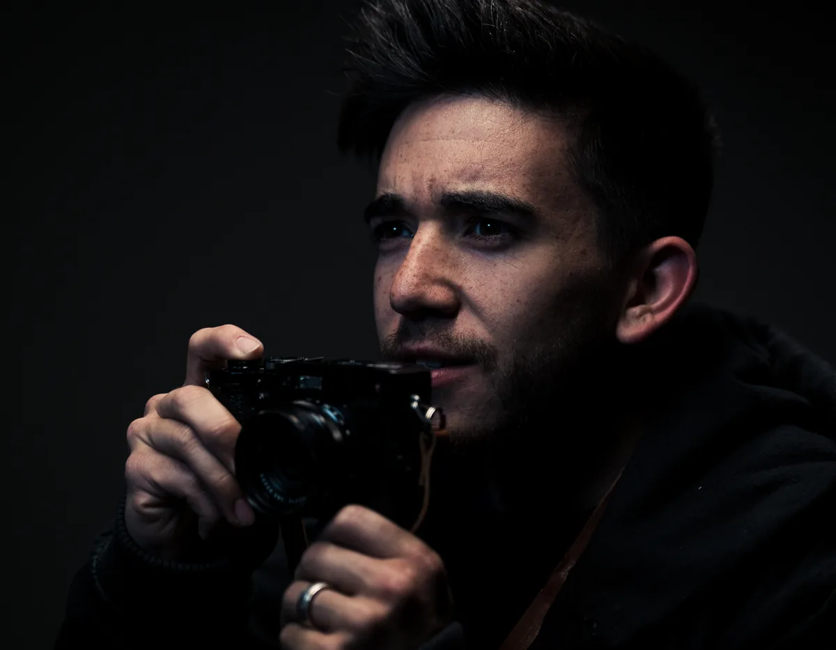 A photographer holding a camera close to his face in low light