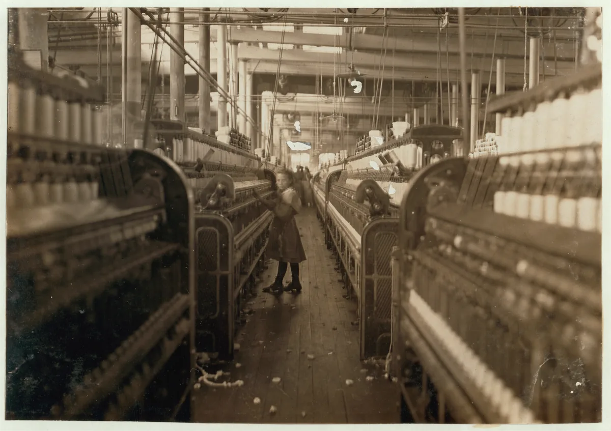 Young spinner in an aisle between machines at Mollahan Cotton Mills in 1908.