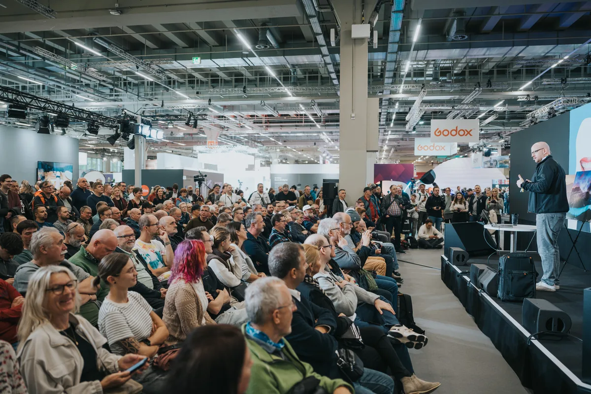 Audience watching a speaker on a stage inside the Imaging World exhibition hall in 2025.