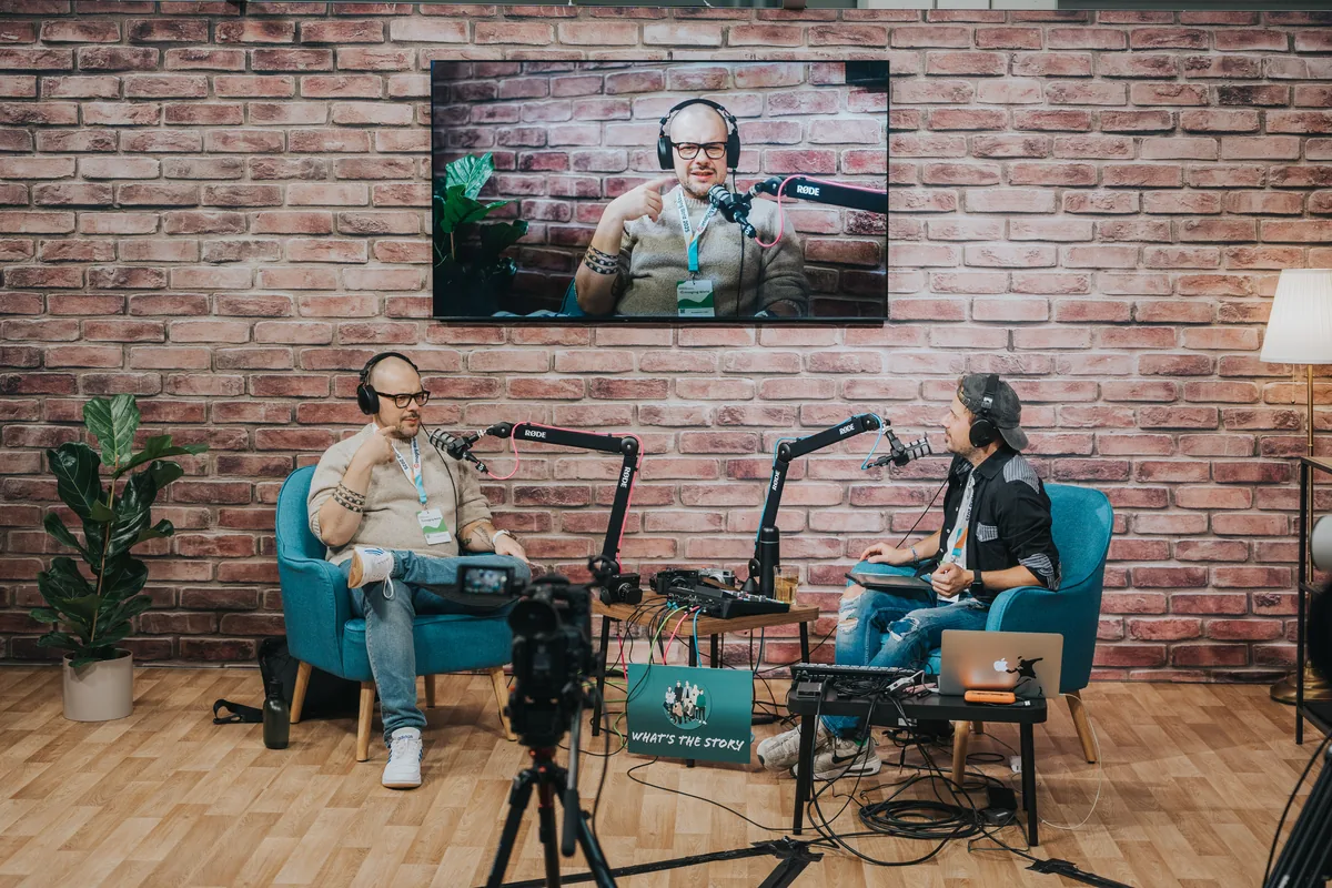 Two people wearing headphones at a microphone-equipped video interview set at Imaging World 2025.
