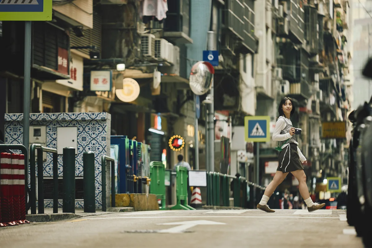 Woman walking across a city street carrying a black Panasonic LUMIX L10.