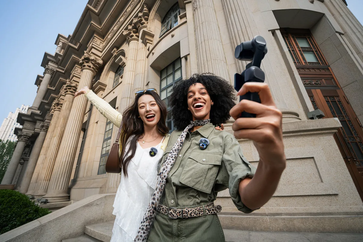 Woman holding a black Insta360 Luna Ultra outside a classical building.