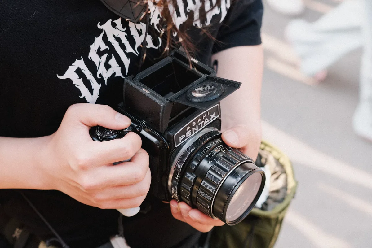 Hands holding a classic medium-format film camera at chest height