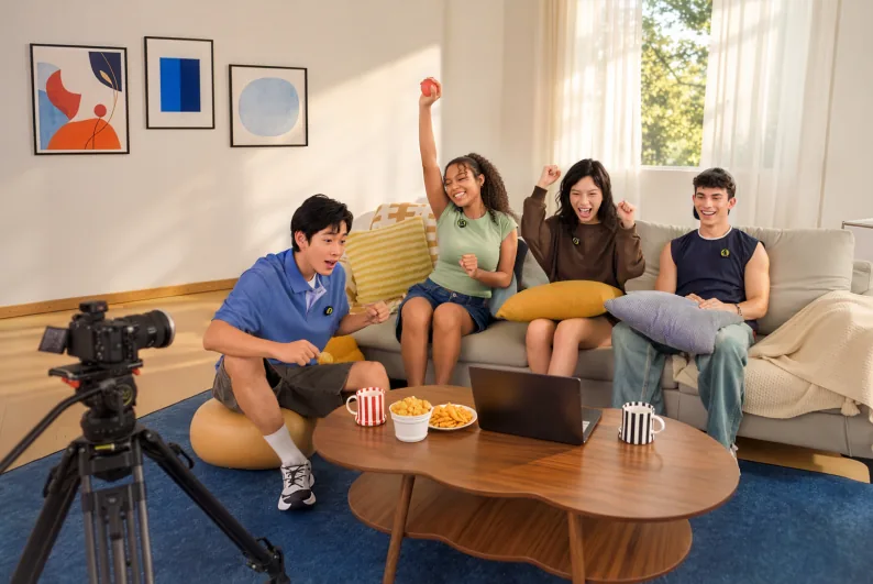 Four people wearing Insta360 Mic transmitters in a staged living-room recording with a camera and laptop.