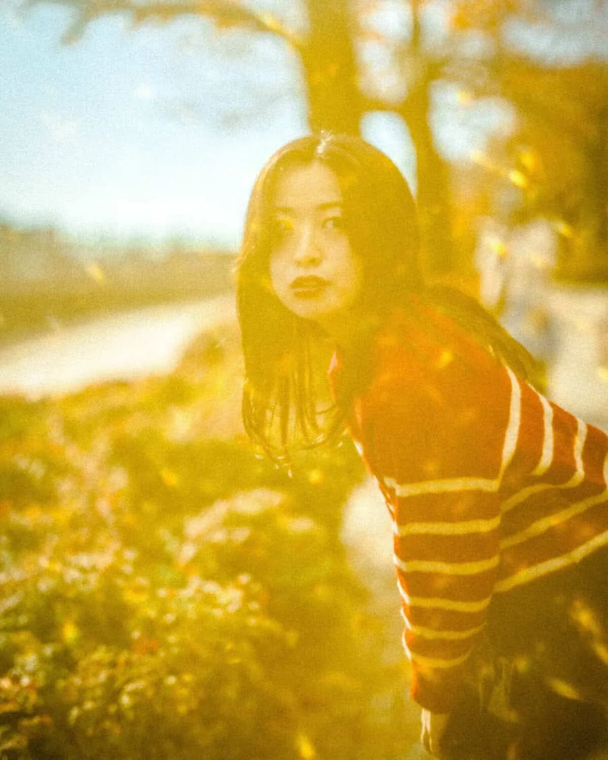 Portrait of a woman in a red striped top with a warm golden haze.