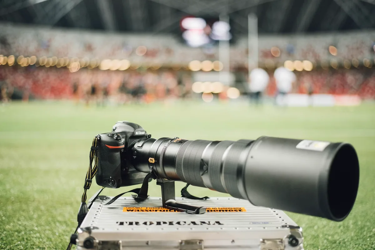 A Nikon camera and long NIKKOR lens at a professional sporting event