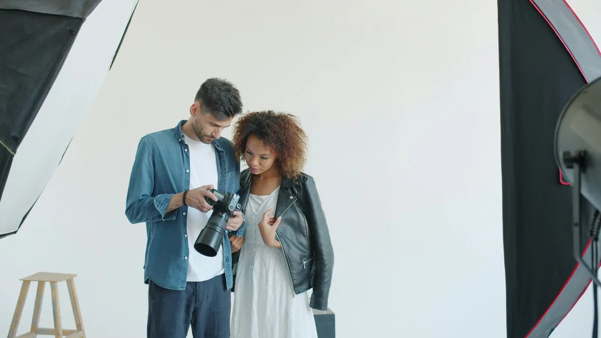 Photographer and model reviewing a camera in a studio.