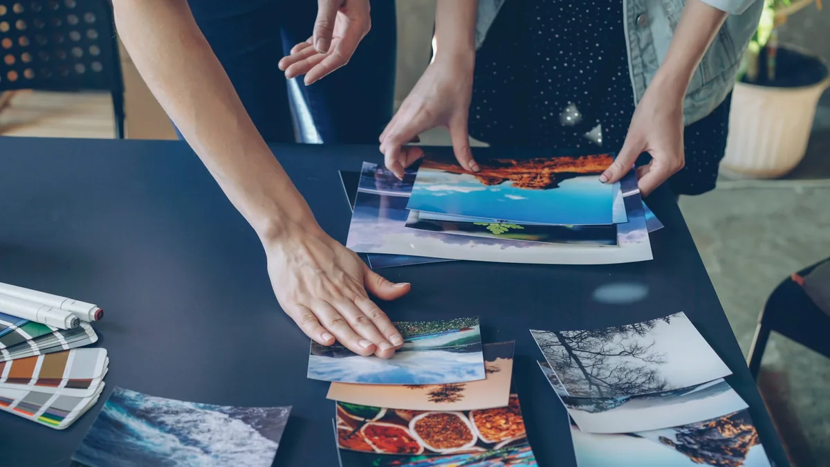 People arranging photographic prints on a table.