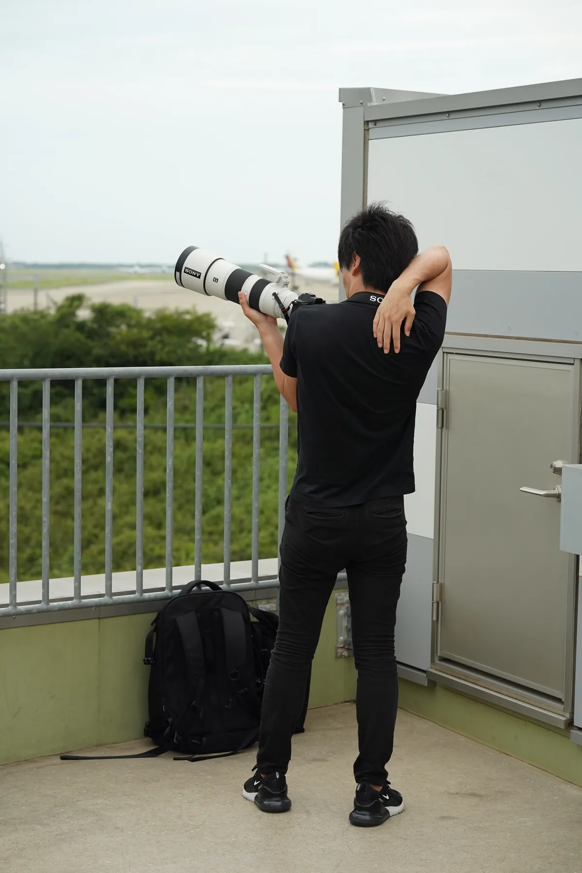 Contextual photograph of a planespotter holding an existing Sony FE 200–600mm G at Narita Airport, not a new prime lens