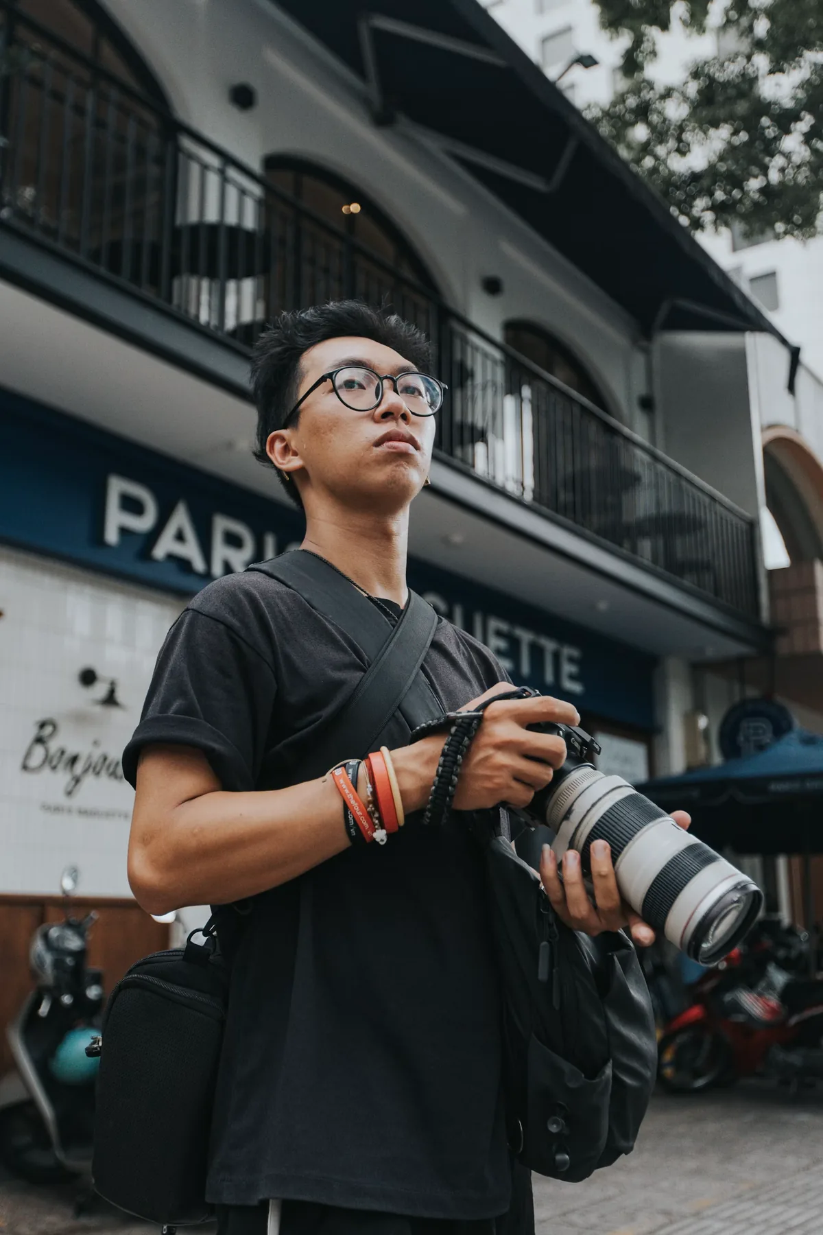 A street photographer looking upward while holding a camera in a city