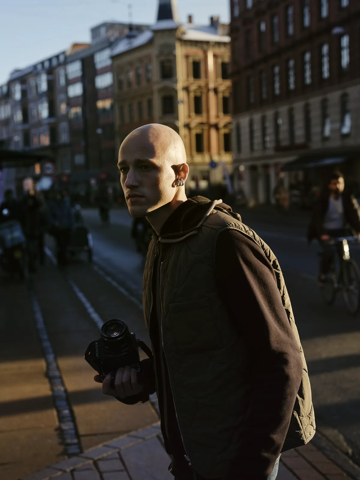 A photographer walking through a city street with a camera in hand