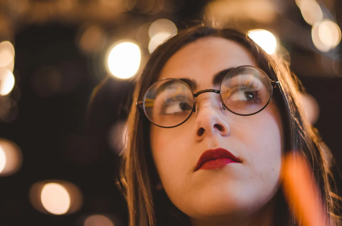 Portrait of a woman wearing round glasses with soft lights behind her