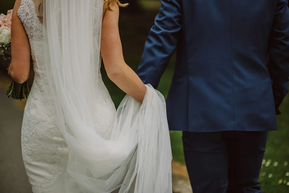 Close view of a wedding couple holding hands while walking