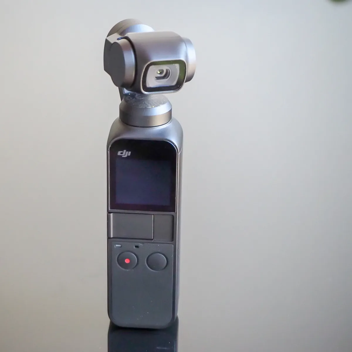 Original DJI Osmo Pocket upright with its gimbal head and screen visible
