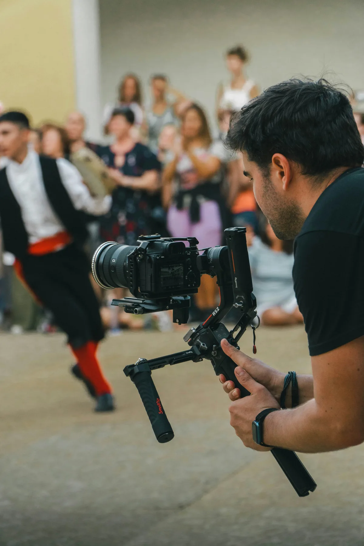 Camera operator holding a mirrorless camera on a full-size gimbal at a dance performance