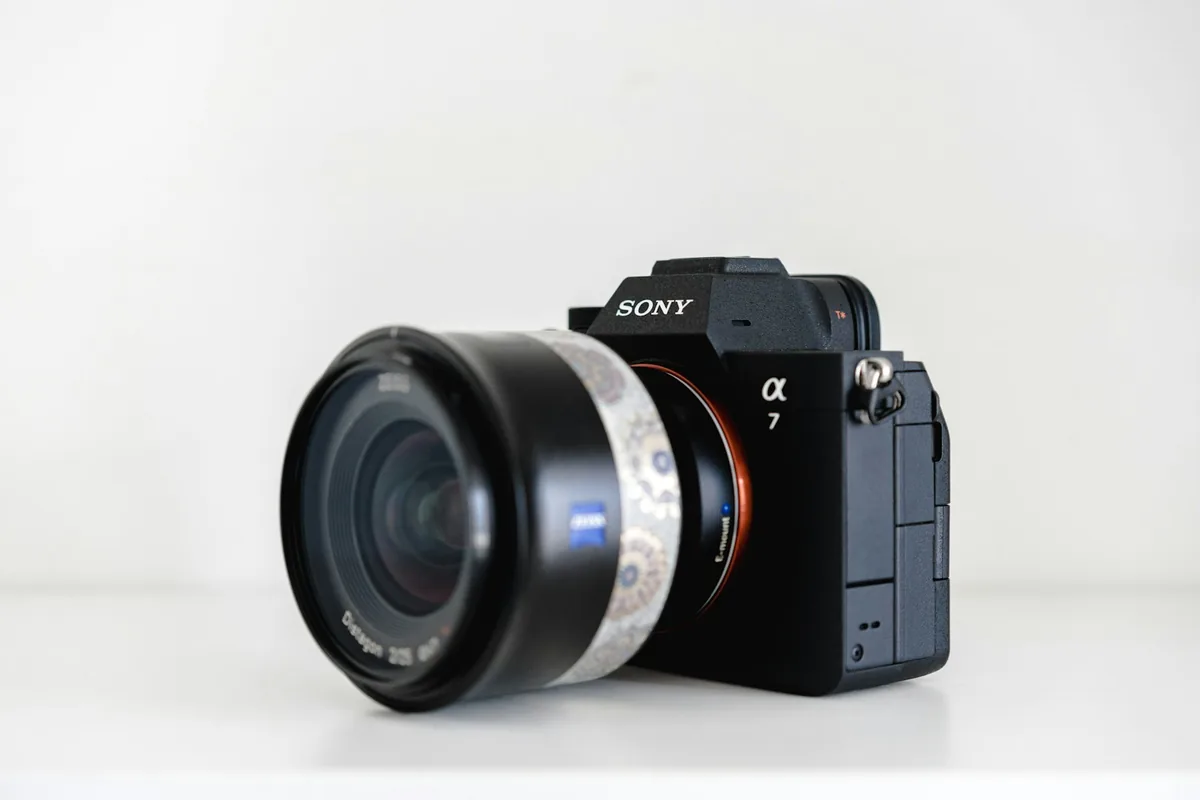 A Sony Alpha 7 full-frame camera with a Zeiss lens on a pale tabletop