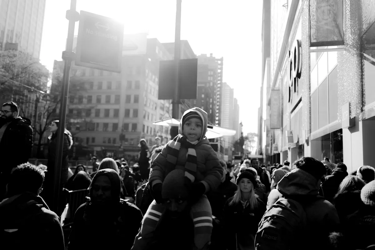 A child on an adult’s shoulders in a winter crowd